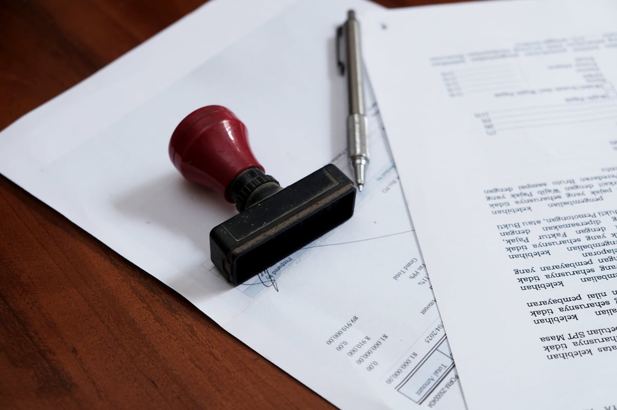 A stamp and pen on a document approved certified contract, law and paperwork permit